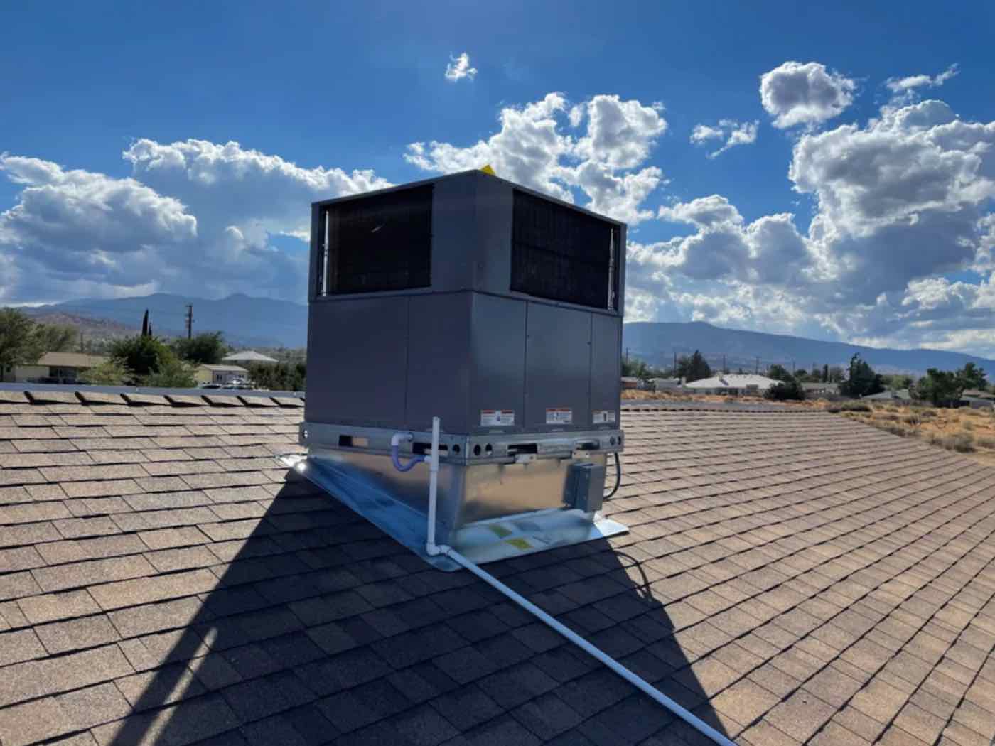A rooftop HVAC package unit under a blue sky.